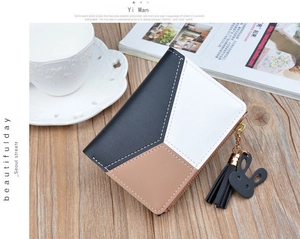 Short tri-color leather wallet with zipper tassel and black rabbit charm on wooden table
