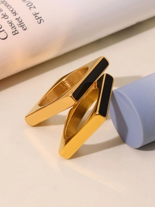 Detailed view of two gold geometric rings with black enamel inlay on a stylish background