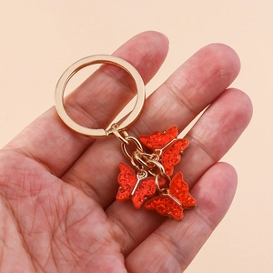 Close-up of red glittery butterfly pendants hanging from a gold circular keychain ring