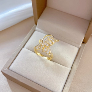 Adjustable golden bow-shaped ring with zircon stones in a jewelry box setting