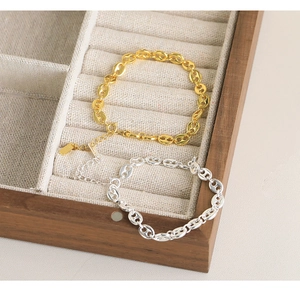 Detail view of gold and silver S925 sterling silver pig nose chain bracelets in jewelry box