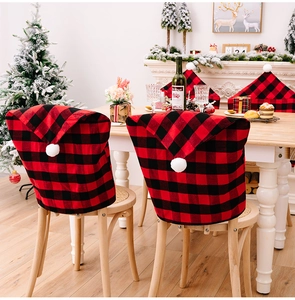 Detail of red and black buffalo plaid Christmas chair covers with white pom-poms on top