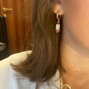 Gold rocket hoop earrings with white rhinestones and red enamel detail on female model