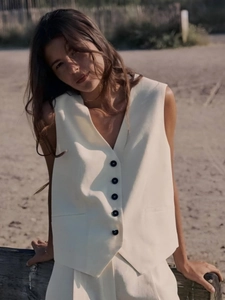 Chic cream-colored V-neck vest and tailored shorts set in a stylish outdoor beach setting