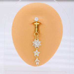 Golden belly ring with crystal flower pendants shown on a silicone body model