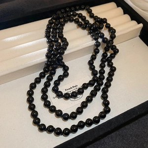 Close-up of long black beaded necklace with high luster finish and manual knotting details