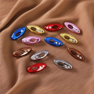 Oval rhinestone brooch pins in vibrant colors on brown pleated fabric background