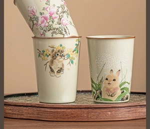 Macro shot of Ru-kiln ceramic cups with ice-cracked glaze and hand-painted cat patterns