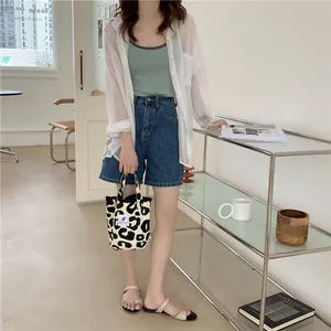 Close-up of leopard print canvas tote bag with brand label and stylish summer outfit