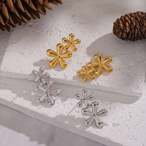 Elegant floral stud earrings in gold and silver finish on a white textured stone background