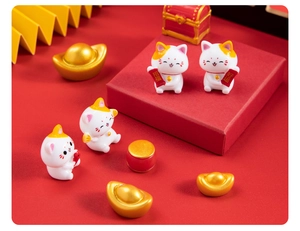 Detailed view of resin lucky cat figurines with gold ingots and a red drum accessory