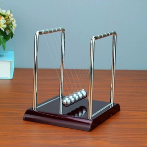 Classic Newton's cradle with silver metal balls on a dark brown wooden base for desk decor