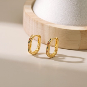 Detailed macro view of gold oval hoop earrings with rainbow pavé zircon stones