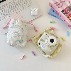 Floral quilted drawstring storage pouches for cameras and electronics in a desktop scene