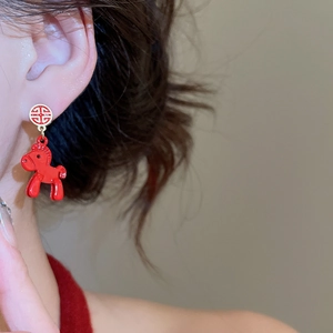 Detailed view of a red pony drop earring with intricate Chinese knot design on model