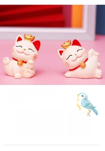 Close-up of cute white resin fortune cats with gold sycees and festive charms