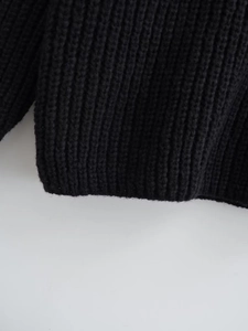 Dettaglio ravvicinato della trama a maglia a coste e dell'orlo di un maglione nero caldo