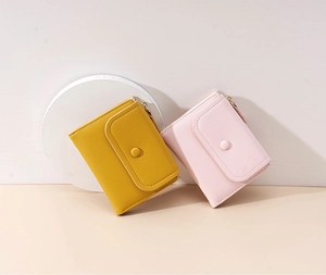 Detail shot of compact PU leather wallets in yellow and pink with litchi texture
