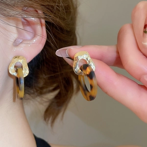 Detailed close-up of a leopard print resin hoop earring with a hammered gold metal texture