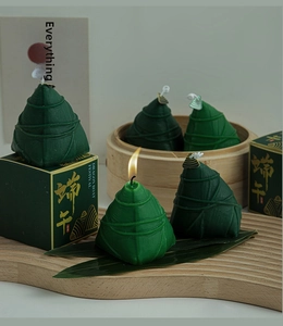 Close-up of green zongzi-shaped scented candle and gift box on wooden tray