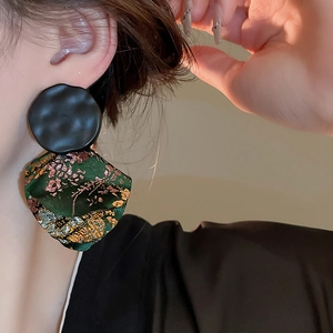 Macro detail of vintage style green brocade fabric earrings with black hammered metal studs