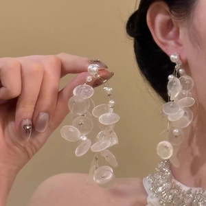 Detail of silver drop earrings with transparent discs and white pearls worn by a model