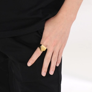 Close-up of golden geometric pyramid ring with polished finish worn by male model