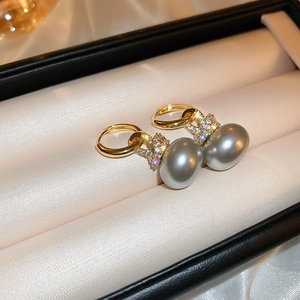 Gros plan de boucles d'oreilles perles dorées avec zircons papillons dans un coffret