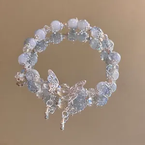 Detail of light blue and white beaded bracelet with silver butterfly pendant on mirror