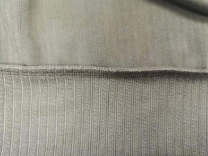 Dettaglio del tessuto a maglia a righe grigio-verde con cuciture a doppio ago e trama