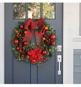 Close-up of Christmas wreath with red plaid bow and pine cones on a grey door