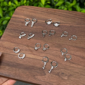 Detailed view of S925 silver earrings with zircon heart and geometric charms on wood