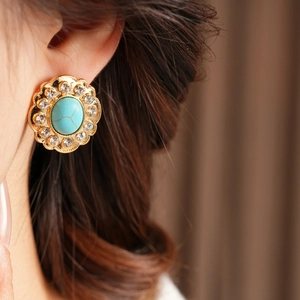 Détail de la boucle d'oreille fleur vintage avec pierre turquoise et strass brillants