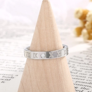 Macro shot of silver titanium ring with Roman numerals and diamond on a wooden stand