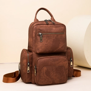Close-up of vintage brown PU leather texture and bronze zipper details on backpack