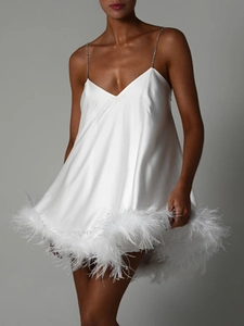 Détails d'une robe en satin blanc avec plumes d'autruche et bretelles chaîne en strass