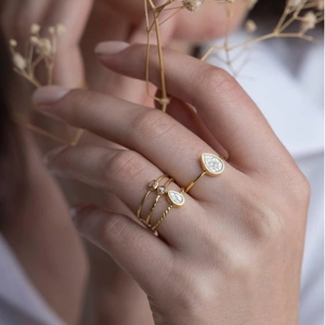 Three-piece stackable gold ring set with teardrop crystals worn by a model