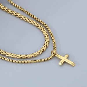 Close-up of double-layer gold cross pendant with Cuban and box chain detail