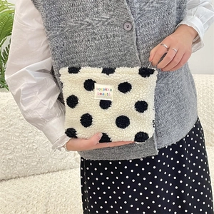 Detail of plush black and white polka dot cosmetic bag with a soft fleece texture