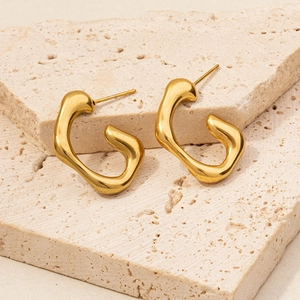 Macro detail of geometric 18K gold plated stainless steel earrings on stone background