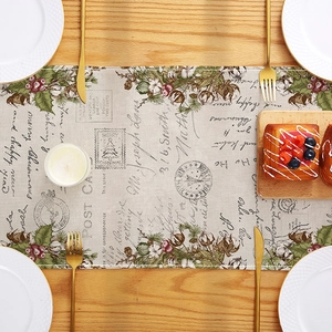 Vintage Christmas table runner with postcard floral prints on a rustic wooden table