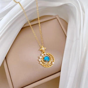 Detail of gold moon and star pendant with blue gemstone and clear crystals on white silk
