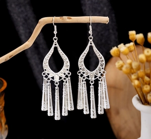 Detail of vintage silver boho drop earrings with fringe tassels hanging on a branch
