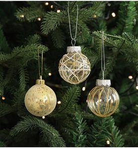 Close-up of 6cm gold and transparent Christmas balls hanging on a lighted tree branch