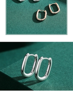 Close-up of geometric U-shaped silver and rose gold hoop earrings on green texture