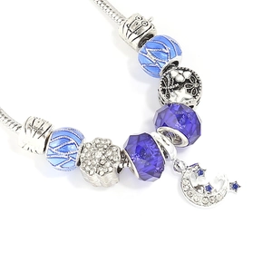 Macro view of blue glass beads and star-moon pendant on a silver snake chain bracelet