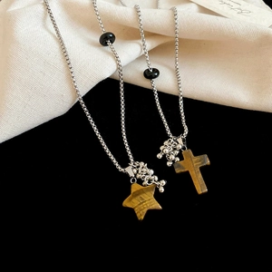 Detail of vintage stainless steel necklaces with tiger eye star and cross pendants