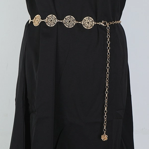 Detail of golden metal chain belt with hollow round patterns and a rose pendant on dress