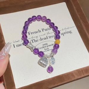 Detail of amethyst beaded bracelet with silver bell charm and cat paw tag in jewelry box