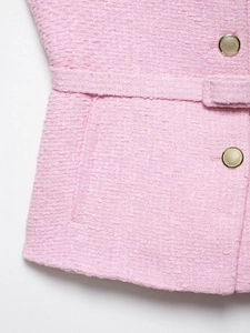 Détail de la texture du tissu en tweed rose avec boutons dorés et ceinture assortie